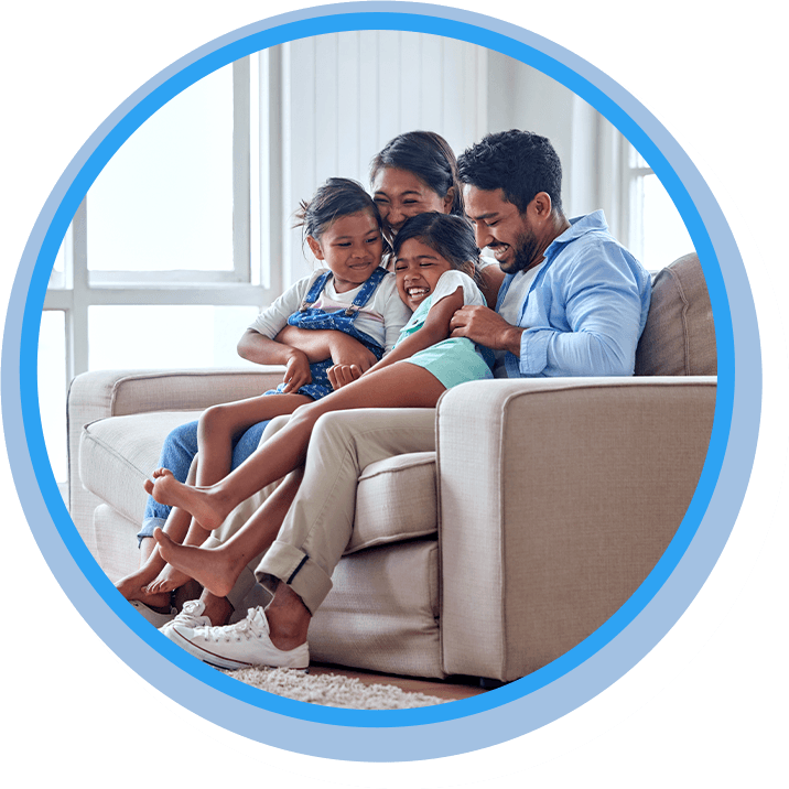 Smiling family of four sitting together on a couch with a tablet