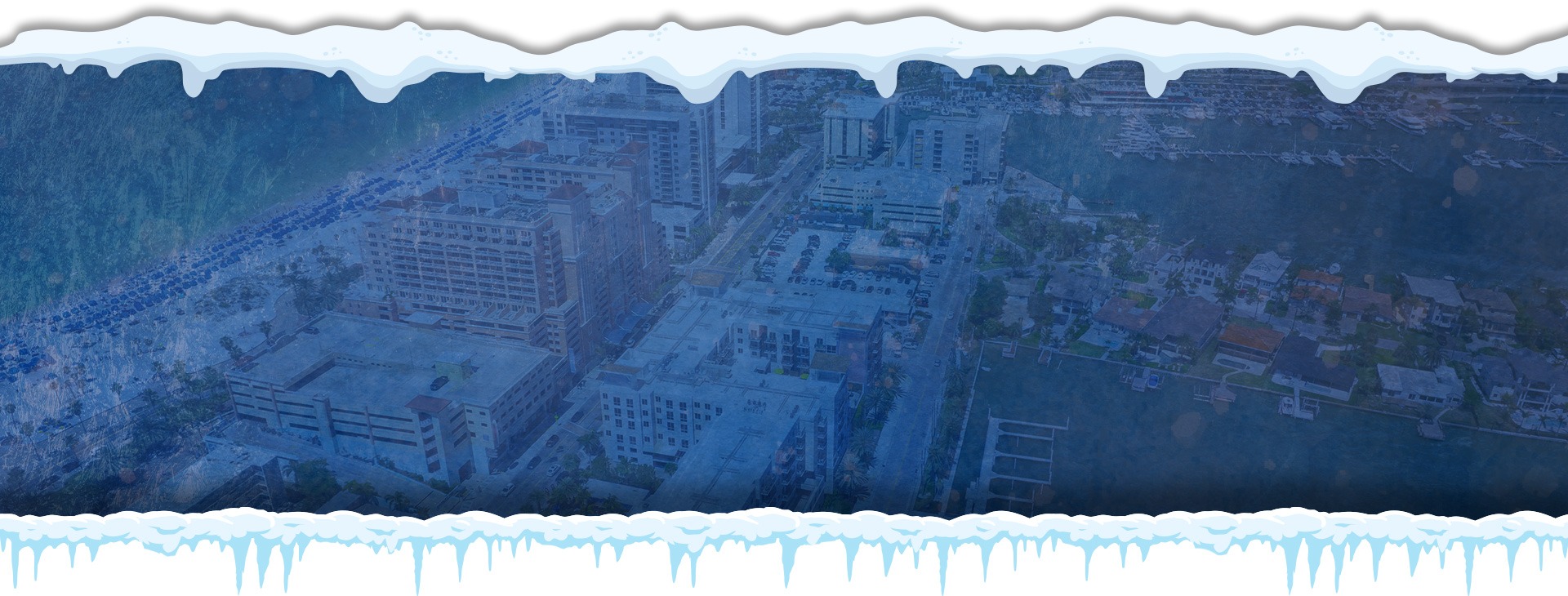 Blue-tinted aerial view of a snowy cityscape under a cloudy sky